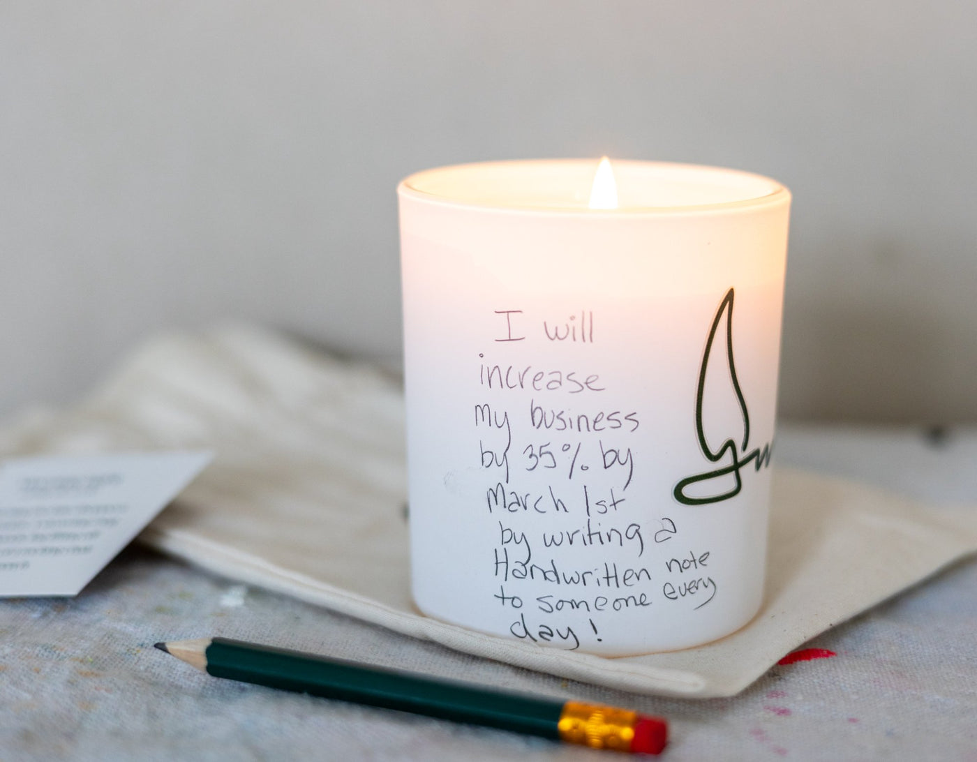 The Manifestation Candle lit with intention written on it